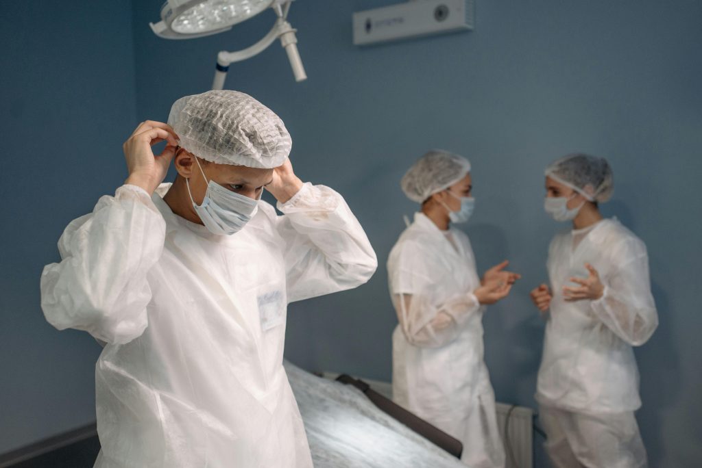 Medical team in protective gear preparing in a hospital room for an operation.